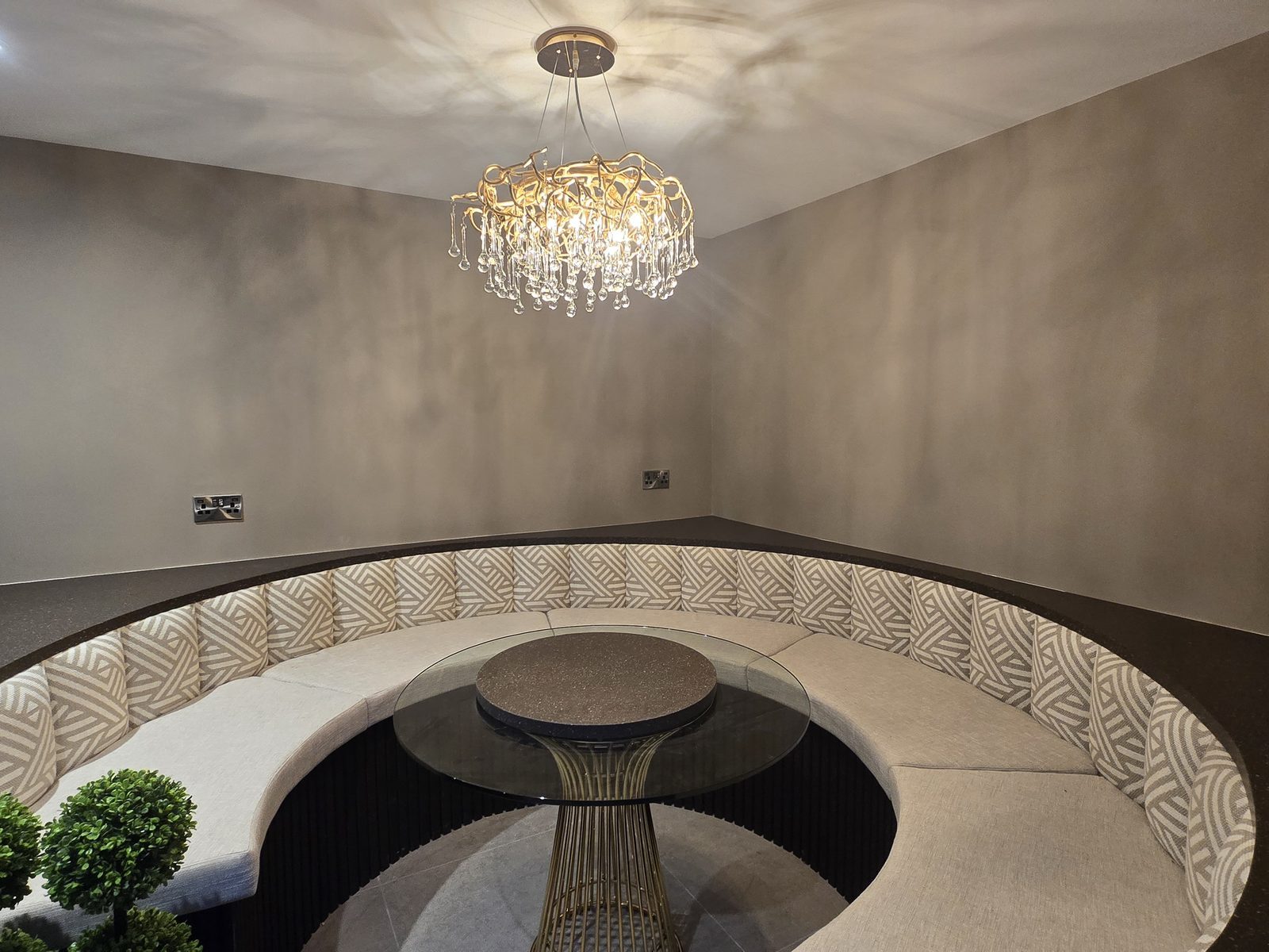 Crystal chandelier and downlights over a curved seating area