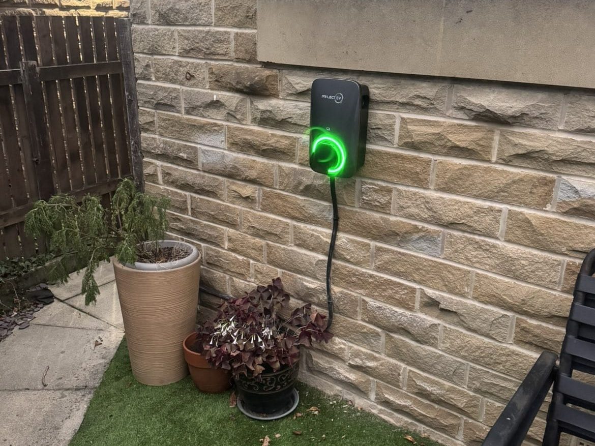 Wall-mounted home EV charger on a stone wall