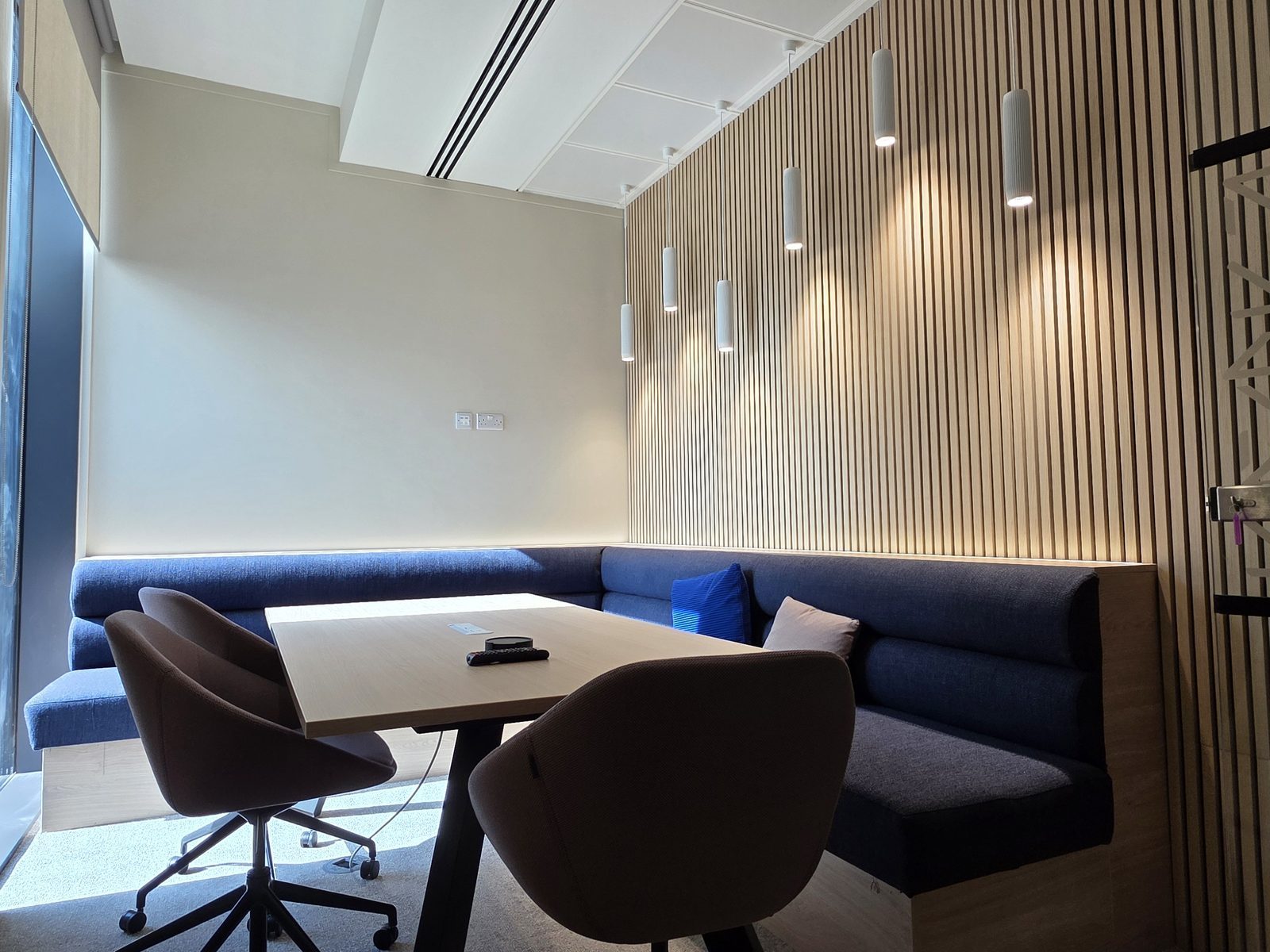 Row of pendant lights over a meeting booth against a slatted wall