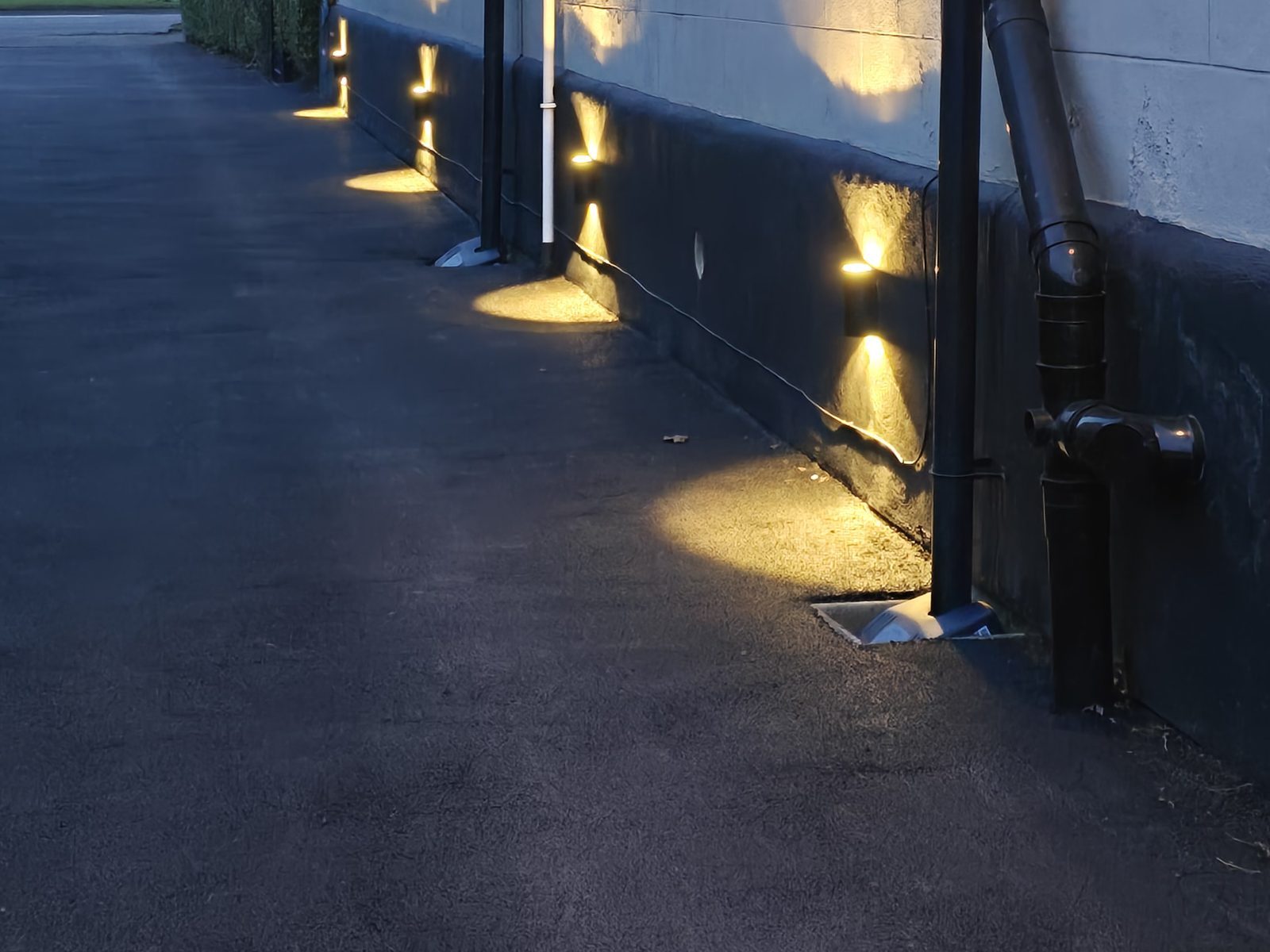 Exterior wall uplights along a path at dusk